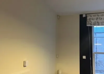 Sensors on the wall and ceiling in a white-walled room.