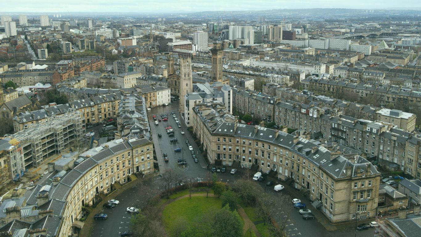 Looking over a curved crescent of terraced flats, then further over the Glasgow cityscape