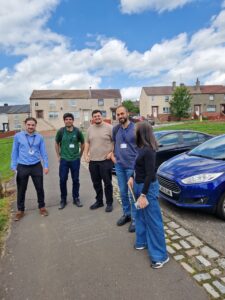 A group of people stand in a car park, next to a housing estate