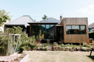 Exterior of a house, showing a square wood-clad extension on the right