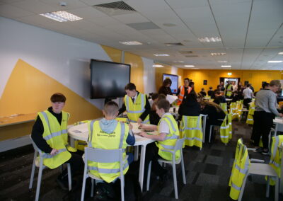 Young people in high-vis vests participate in an activity around a table