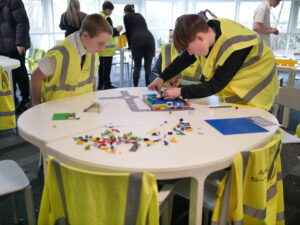 Young people in high-vis vests participate in an activity around a table