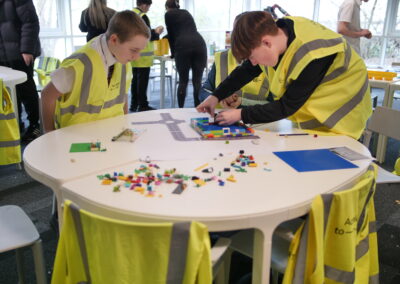 Young people in high-vis vests participate in an activity around a table