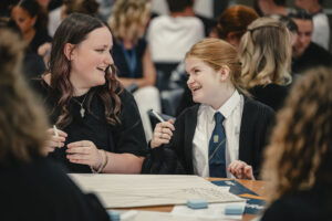 A pupil and facilitator are talking and smiling at each other