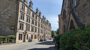 Photo showing row of old tenement-style flats, with the corner of a church visible in the foreground.